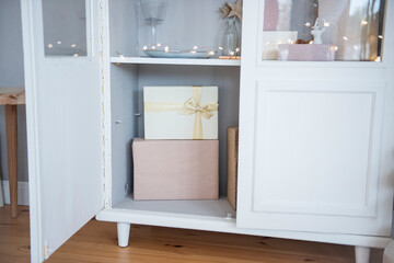 Pink holiday boxes tied with a gold ribbon in a white wooden sideboard. Mock up. copy space