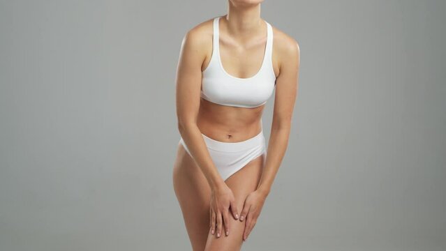 Young, fit and beautiful blond woman in white swimsuit posing over grey background. Healthcare, diet, sport and fitness concept.