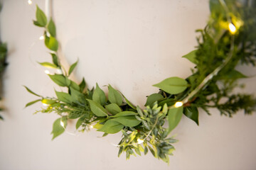 On gray concrete wall, there are three laconic, elegant, green wreaths made from natural materials.