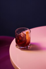 cocktail with alcohol and whiskey and ice and fresh orange peel in a rocks glass, on a white table