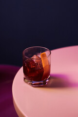 cocktail with alcohol and whiskey and ice and fresh orange peel in a rocks glass, on a white table