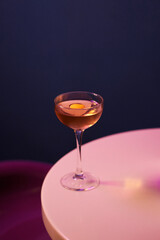cocktail with alcohol and fresh orange peel in chilled cocktail glass, on white table