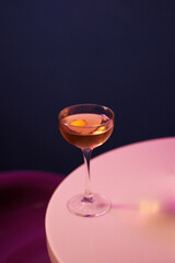 cocktail with alcohol and fresh orange peel in chilled cocktail glass, on white table