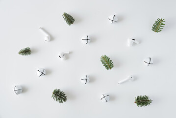 Christmas pattern made of white Christmas bells, wireless headphones and fir branches.
