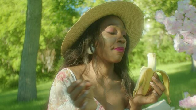 Black Woman Eating Banana Chewing In Park Dolly In Close Up