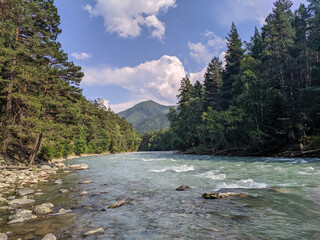 View of the Zelenchuk River with a rocky bottom in the village of Arkhyz against the backdrop of the Caucasus Mountains. Arkhyz, Karachay-Cherkessia, Russia