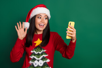 Photo of excited funky girl dressed ugly print red x-mas pullover headwear recording self video modern gadget isolated green color background