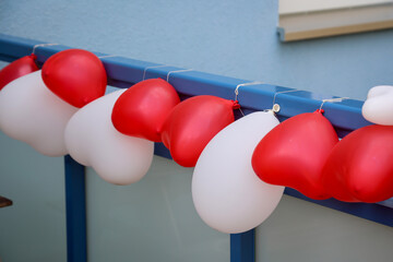 Luftballons in Herzform an einem Geländer befestigt zur Dekoration bei einer Hochzeit.
