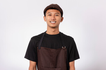 Handsome barista asian man wearing brown apron and black t-shirt isolated over white background standing with crossed arms smiling confident looking at camera