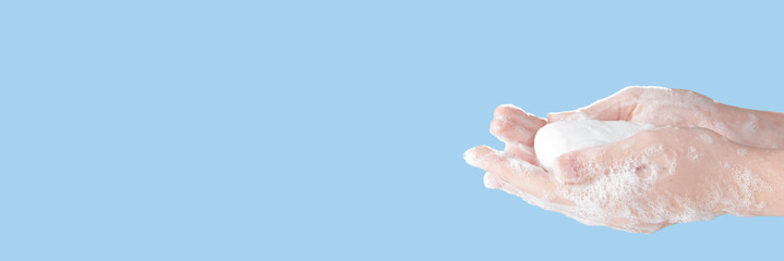 White soap in women's soapy hands on a blue background. Photo with copy space.