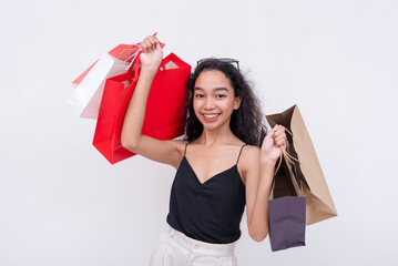 An elated asian woman holding shopping bags on both hands after going on a shopping spree. Isolated...