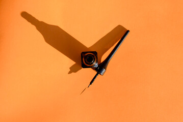 Black eyeliner on an orange background. Cosmetic makeup tools.