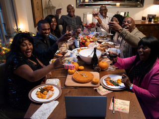 Family having video call and raising toast during Thanksgiving dinner
