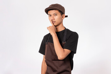 Handsome barista asian man wearing brown apron and black t-shirt isolated over white background...