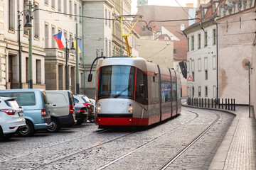 Naklejka na ściany i meble Modern Tram in old stree of Prague in a summer day, Czech Republic. The Prague tram network is the third largest in the world. Passenger Eco-friendly electric transport connection in the Europe City