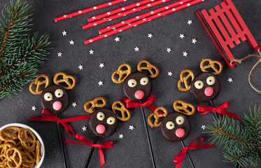 Cute idea Christmas treats - cake pops Santa's reindeers made from cookies in chocolate and crackers on gray table, Flat lay, Top view