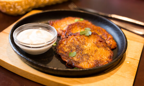 Fried grated potato pancakes with sour cream on frying pan
