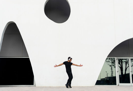 Energetic man dancing on street with arms outstretched