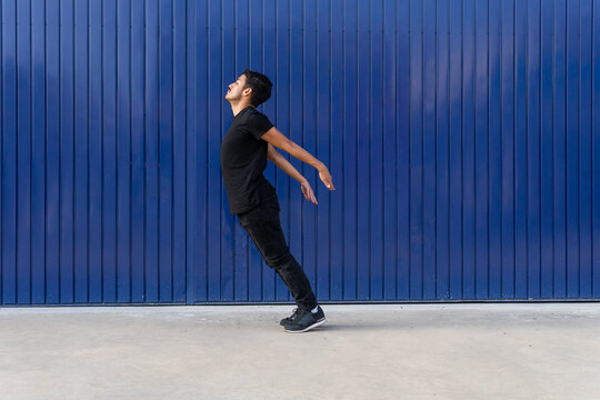 Man jumping against blue fence