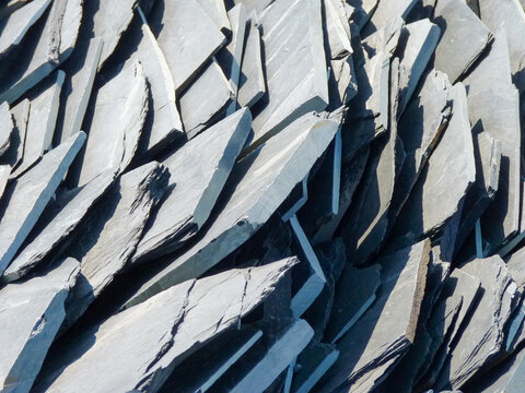 Grauer d&uuml;nner Schieferstein in schr&auml;ger Aufschichtung . Schieferplatten aufgeschichtet in einer stabilen Anordnung . Schiefer slate plates in nature . interesting geoemtric stone arrangement Schistose