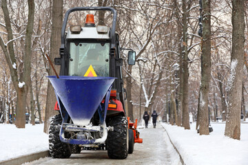 Snow plow machine in a park, street cleaning in winter city