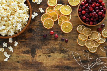 Supplies for making Christmas garland by stringing popcorn, cranberries, dried orange and lemon slices