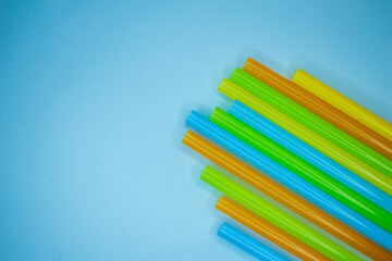 Colorful beverage straws or pipette on blue background. Top view of straws. Copy space.