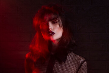 Beauty front portrait of young female model with makeup in red neon colourful studio light,...
