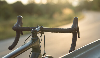 Road bike parked on a beautiful road sunset, warm light with copy space.