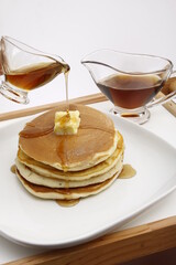 Syrup being poured on pancake on a breakfast tray