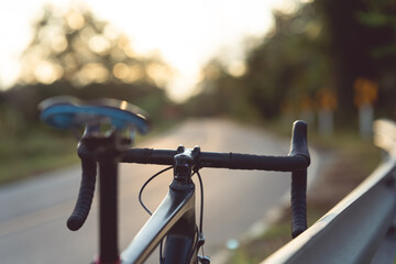 Road bike parked on a beautiful road sunset, warm light with copy space.