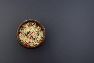 A mix of three types of rice in a round bowl on a gray background. Brown, red, black rice. 