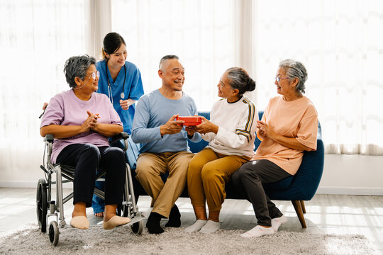 Asian Elderly Man Receiving Gift Boxes From Friends On Special Occasion, Happy Lifestyle After Retirement