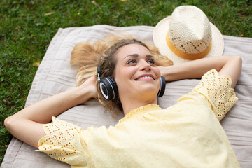 woman lies on the grass listens to music on headphones