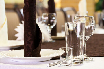 table set in the restaurant. White tablecloths, glasses and shot glasses, close-up, selective focus.