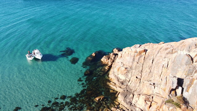 Two white boats next to a rock formation in a lagoon. Location Dunsborough in South-west Western Australia. Beautiful blue clear water and rocks.