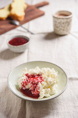 Homemade ricotta soft cheese or cottage cheese served with raspberry jam and fresh bread and cup of cocoa on linen tablecloth. Healthy cozy breakfast. Selective focus - 546896224