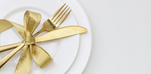 Christmas table setting close up view. Golden cutlery and decoration on white dishes