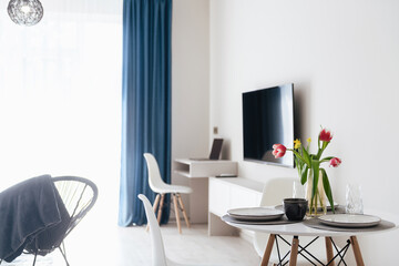 a table with flowers, a TV and blue curtains in a new house