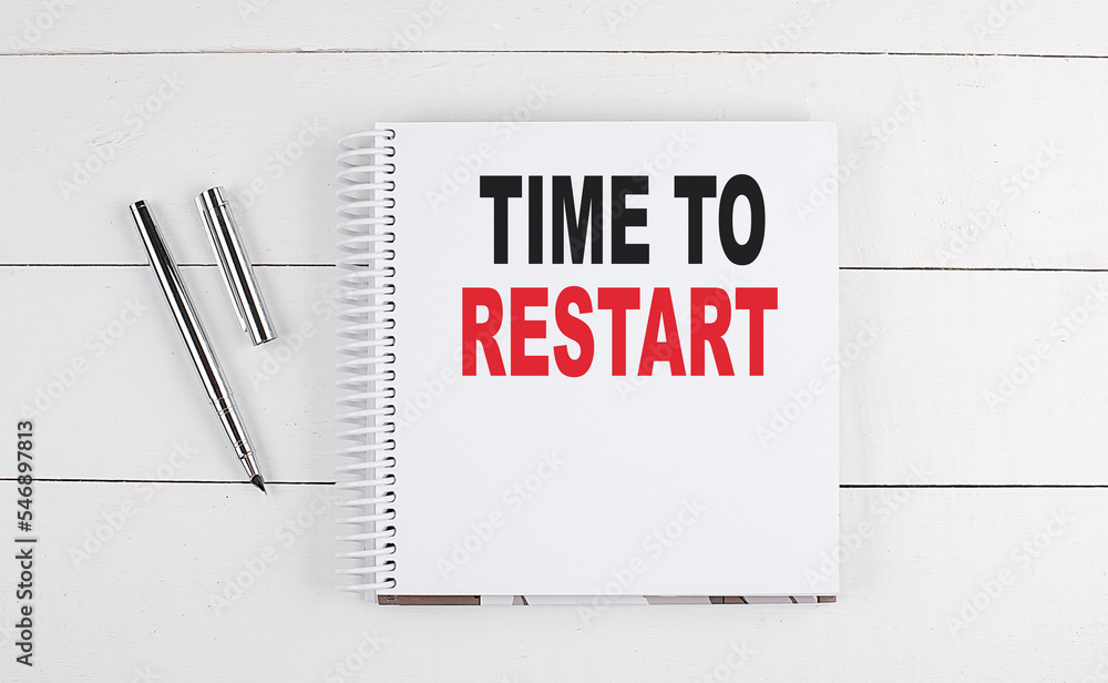 Poster time to restart text written on notebook on the wooden background