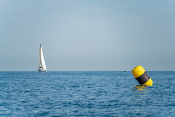 Buoy in foreground with blurred sailboat in the background