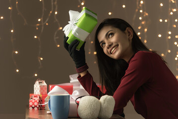 Young asian beautiful woman in winter style sit and hold big gift box on bokeh background.