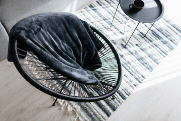 a large black wicker chair with a soft cover in a new house
