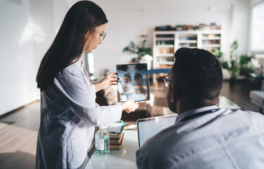 Obraz premium Woman doctor with x ray film of patient standing near male colleague in clinic