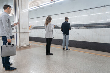 various subway passengers waiting for the train on the platform.