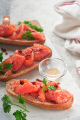 Sandwiches with salted salmon. Open sandwiches from cereal or whole grain rye bread with salted salmon, sesame seeds and dried tomato on white marble stand. Seafood. Healthy food. Scandinavian cuisine