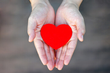 hands hold red heart with loving care , self love and willing to share and give love to others. pay it forward human touch