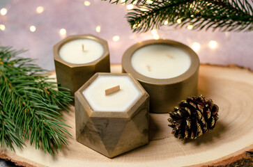 Decorative candles in a pot and fir branches and cones against the background of garlands, a festive composition