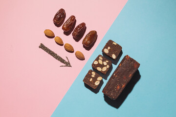 Protein date fruit candy bars fitness with nuts and fruit almond and chia poppy seeds top view on blue pink background with copy space and place for text