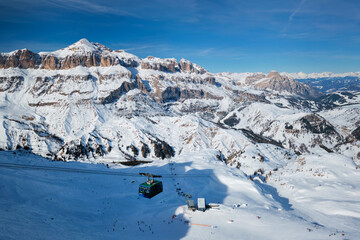View of a ski resort piste with people skiing in Dolomites in Italy with cable car ski lift. Ski...